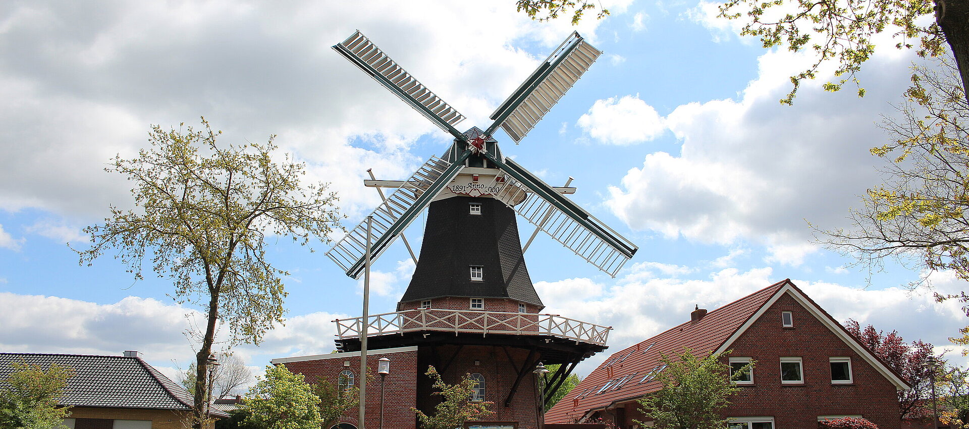 Frontansicht der Mühle Idafehn, rechts davon ein Haus, davor ein Parkplatz und Bäume