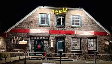 Das Bild zeigt das Restaurant Mediterran in der Nacht. Der Eingangsbereich sowie einige Teile des Hausfassade sind Hellbeleuchtet und bringen so den Schriftzug des Restaurants zur Geltung.